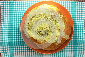 Stuffed bread with the chicken and melted cheese on the orange plate and red, brown background