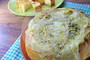 Stuffed bread with the chicken and melted cheese on the orange plate and red, brown background