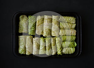 Stuffed cabbage rolls in a baking tray on a black background. Selective focus.