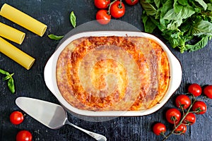 Stuffed cannelloni with bechamel sauce. Cannelloni pasta baked with meat, cream sauce, cheese on a black background. Top view,