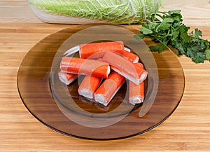 Stuffed crab sticks on dark glass dish among of vegetables