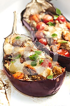 Stuffed eggplants on a wooden table with fresh basil