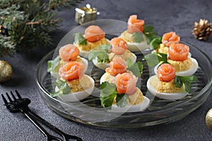 Stuffed eggs with salted salmon and cheese, a delicious festive snack on a dark background. Closeup