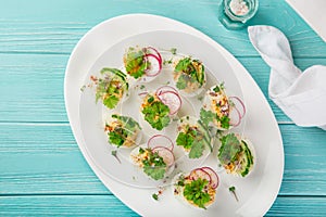 Stuffed eggs on whte plate for easter table, blue background