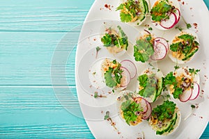 Stuffed eggs on whte plate for Easter table, blue background