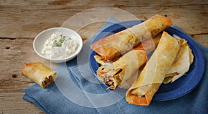 Stuffed filo or yufka dough rolls and curd cheese, pastry with a spicy meat filling, blue napkin on a rustic wooden table