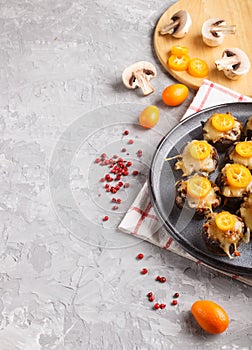 Stuffed fried champignons with cheese, kumquats and green peas on a gray concrete background. side view, copy space