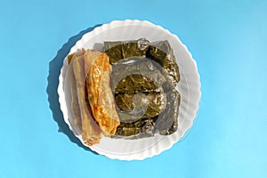 Stuffed Grape leaves and cabbage on white plate on blue bright background