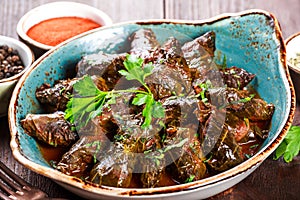 Stuffed grape leaves with rice and herbs on plate on wooden background - Dolma, tolma, sarma. photo