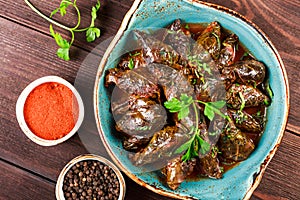 Stuffed grape leaves with rice and herbs on plate on wooden background - Dolma, tolma, sarma. photo