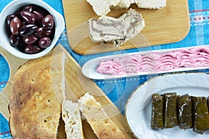 Stuffed grape leaves with rice,lagana bread on cutting board, taramosalata on olive dish and kalamon olives on bowl ana sunflower