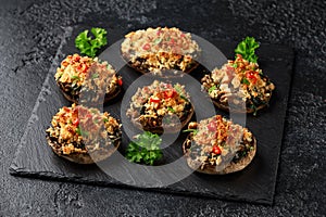 Stuffed mushrooms with spinach, bread crumbs and cheese on stone board