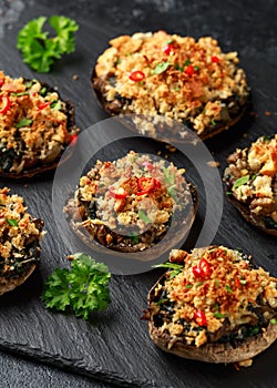 Stuffed mushrooms with spinach, bread crumbs and cheese on stone board