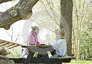 Stuffed people sitting at picnic table under tree in Texas