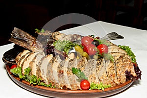 Stuffed pike on a plate of vegetables and leaves of green salad
