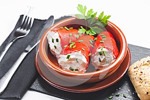 Stuffed piquillo peppers in earthenware casserole on white background