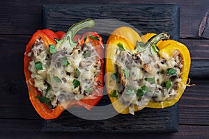 Stuffed sweet peppers with rice mushrooms and cheese with herbs. Baked halves of red and yellow peppers with filling