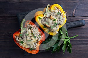 Stuffed sweet peppers with rice mushrooms and cheese with herbs. Baked halves of red and yellow peppers with filling