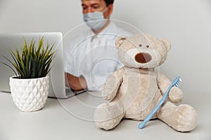 Stuffed Teddy Bear with toothbrush at dentist`s office. Child healtcare concept