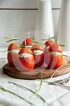 Stuffed tomato with chicken, garlic and cream cheese pasta lying on a brown wooden board