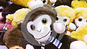 A stuffed toy monkey with big black eyes lying with a bunch of other stuffed toys.