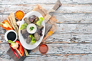 Stuffed vine leaves, dolma, sarma, dolmadakia, dolmades are a white plate. On the old wooden background. Free space for text.