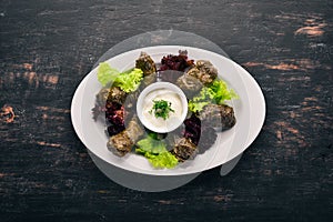 Stuffed vine leaves, dolma, sarma, dolmadakia, dolmades are a white plate. On the old wooden background. Free space for text. photo