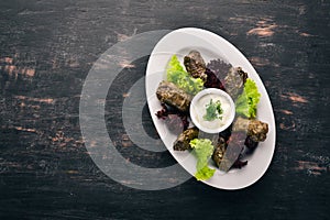 Stuffed vine leaves, dolma, sarma, dolmadakia, dolmades are a white plate. On the old wooden background. Free space for text. photo