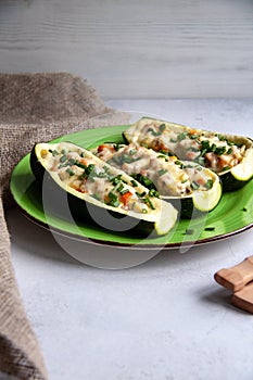 Stuffed zucchini with turkey, tomato, cheese and spring onion on a green plate