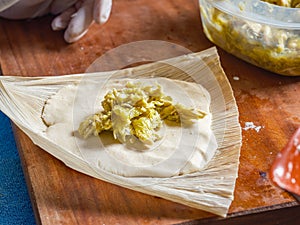 Stuffing and wrapping a Tamale with chicken meat in a corn husk