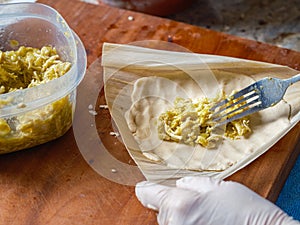 Stuffing and wrapping a Tamale with chicken meat in a corn husk