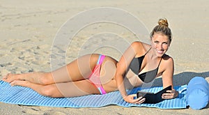 Stuning young woman on beach - reading in bikini