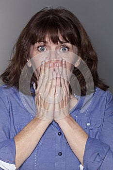 Stunned attractive mature woman hiding her mouth