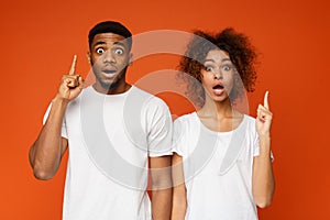 Stunned black man and woman pointing upward with opened mouths