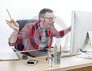 Stunned designer looking at computer screen with pen in hand