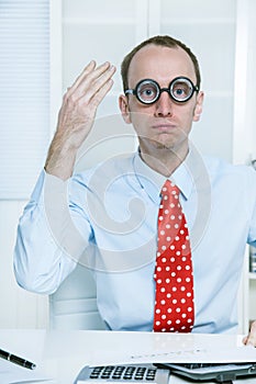 Stunned man with big glasses and a red tie at work like a comedian, bookkeeper or manager with good ideas.