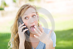 Stunned Woman Outdoors Talking on Her Smart Phone.