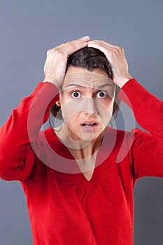 Stunned woman with wide eyes holding her head for mistake