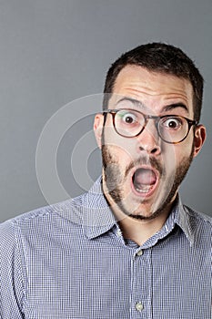 Stunned young bearded businessman with eyeglasses and mouth open