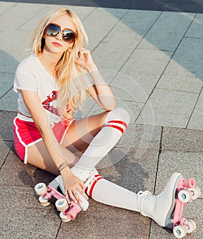 A stunner smiling summer closeup portrait of young happy woman posing in a vintage roller skates, sunglasses, T-shirt shorts