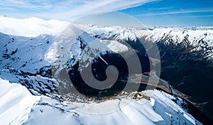 Stunning aerial image of the mouth of the glacier at Lake Wanaka surrounded by snow capped mountains taken on a sunny winter day,