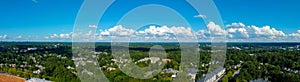 A stunning aerial panoramic shot of vast miles of lush green trees with apartments and office buildings in the trees with blue sky