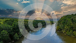 A stunning aerial shot of the Chattahoochee river surrounded by lush green and autumn colored trees with powerful clouds