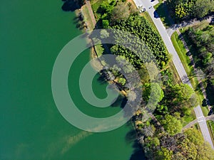 A stunning aerial shot of the lush vast green lake water and the lush green trees and plants on the banks of the lake