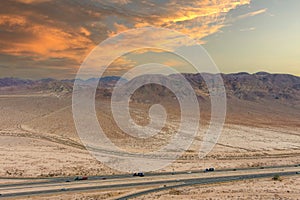 A stunning aerial shot of majestic mountain ranges in a vast desert land with powerful clouds with freeways