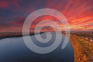 A stunning aerial shot of the vast flowing waters of the Mississippi river at sunset with powerful clouds and red sky