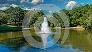 A stunning aerial shot of a water fountain in the middle of silky green lake water