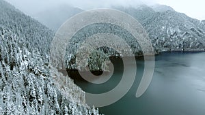 Stunning aerial view of flight above winter forest and lake in the mountains.