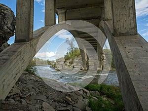 Stunning arched concrete bridge crossing a crystal clear trout stream in Alberta