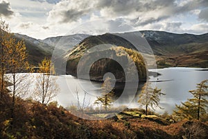 Stunning Autumn Fall landscape of Hawes Water with epic lighting and dramatic sunlight in Lake District